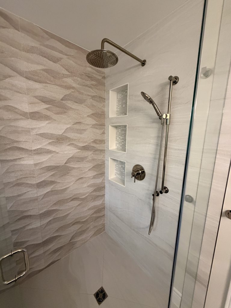 Completed bathroom by Arkia Constructions with a freestanding tub, large-format tile and a full-height glass curbless shower